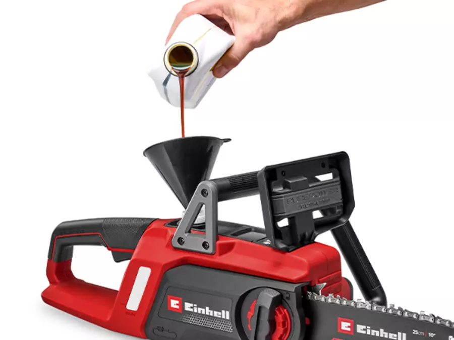 Рука заливає оливу в резервуар для оливи акумуляторної бензопили Einhell GE-LC 18/25 Li BL.