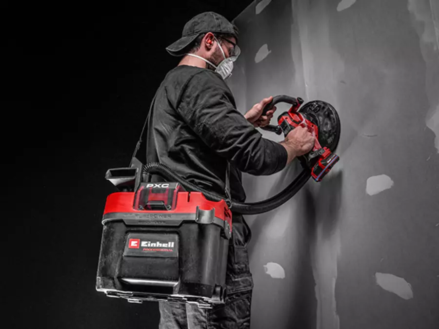 Людина носить пилосос Einhell TP-VC 18/10 Li BL L-Solo на ремені під час роботи.