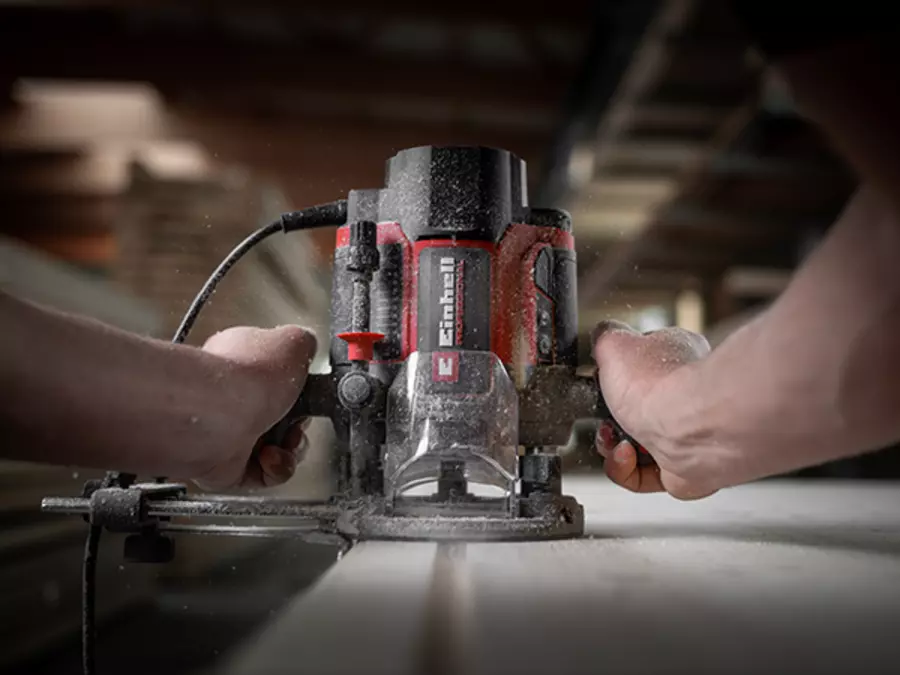 Фрезер Einhell TP-RO 1400 E під час використання; обидві руки надійно керують пристроєм для ергономічної роботи.