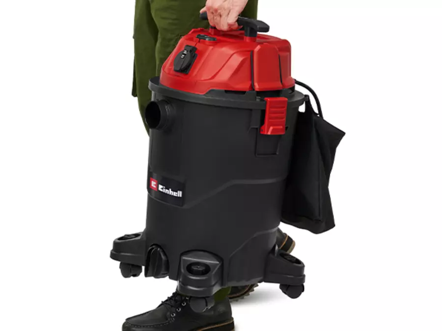 Один человек несет пылесос Einhell TC-VC 3055 A для сухой и влажной уборки за ручку на спине.